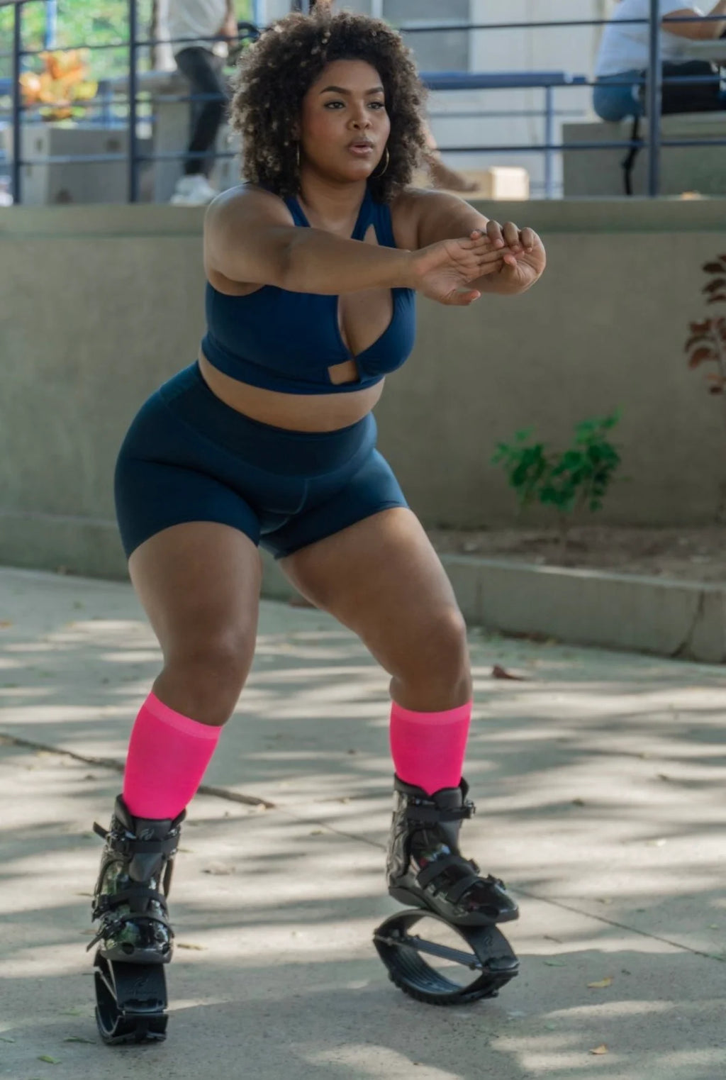 Person wearing a blue athletic outfit with pink socks and black roller shoes outdoors.